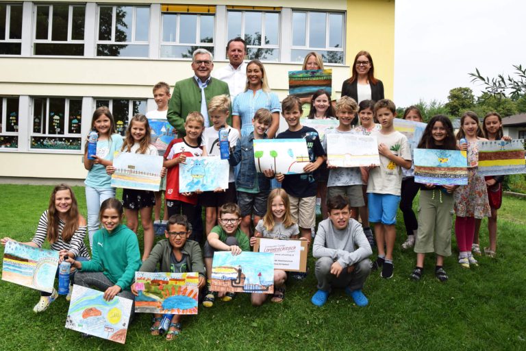 Schüler der Volksschule Rehhof zeigen stolz ihre Wasserprojekte mit Tablets und Kunstwerken.